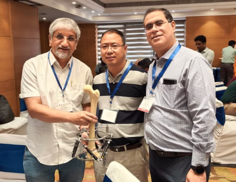 Surgeons at a conference holding a bone model demonstrating an external fixator device